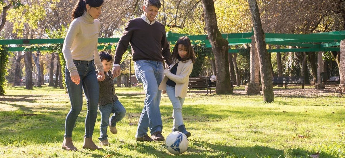 A family plays soccer together in a sunny park, enjoying quality time outdoors.
