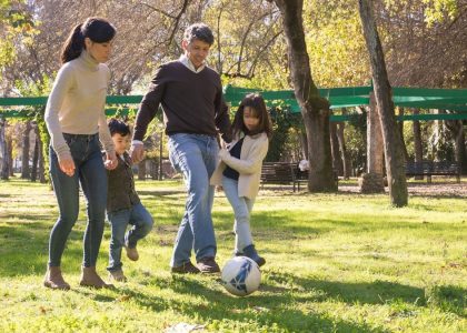 A family plays soccer together in a sunny park, enjoying quality time outdoors.